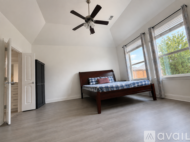A bedroom with a bed, a ceiling fan, and a door leading to another room.