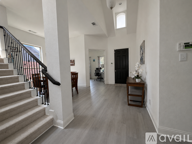 A spacious hallway with a staircase and a door leading to another room.