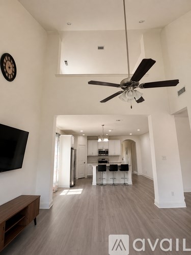 A modern living room with a ceiling fan and a television mounted on the wall.