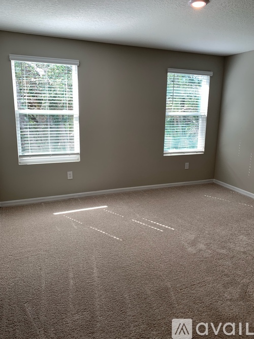 A room with two windows and carpeted floor.