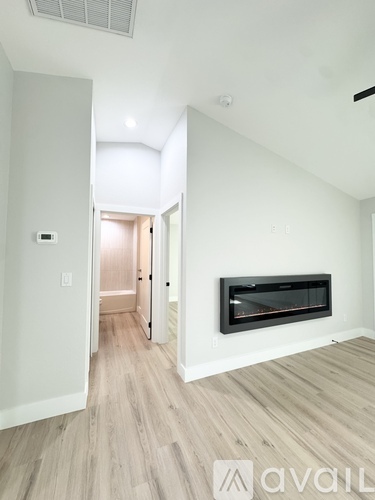 A room with a fireplace and a doorway leading to another room.