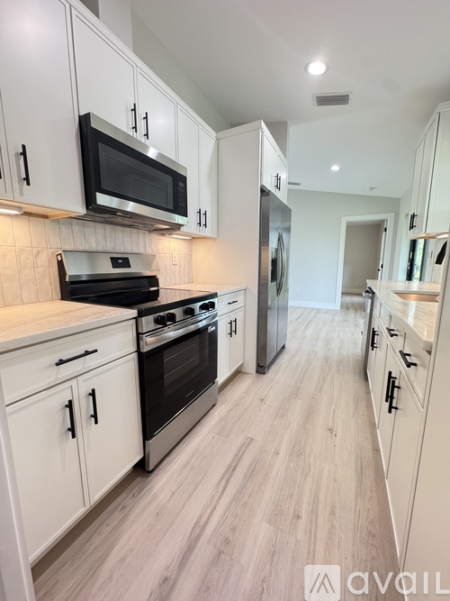 A kitchen with white cabinets and black appliances.