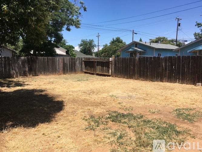A backyard with a wooden fence and a blue house in the background.