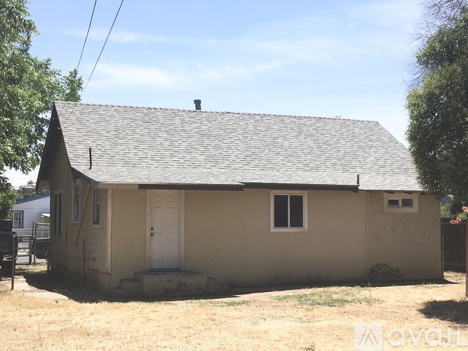 A small house with a white door and a window is surrounded by grass.