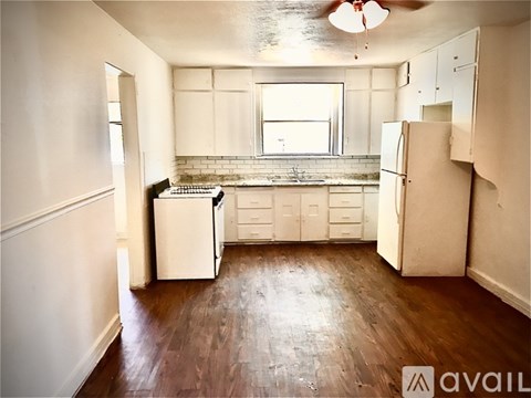 A kitchen with white appliances and wooden floors.