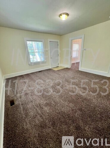 A room with a carpeted floor and a window with blinds.