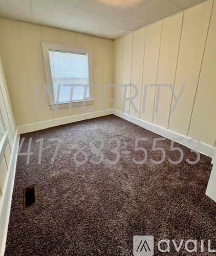 A room with a window and a carpeted floor.