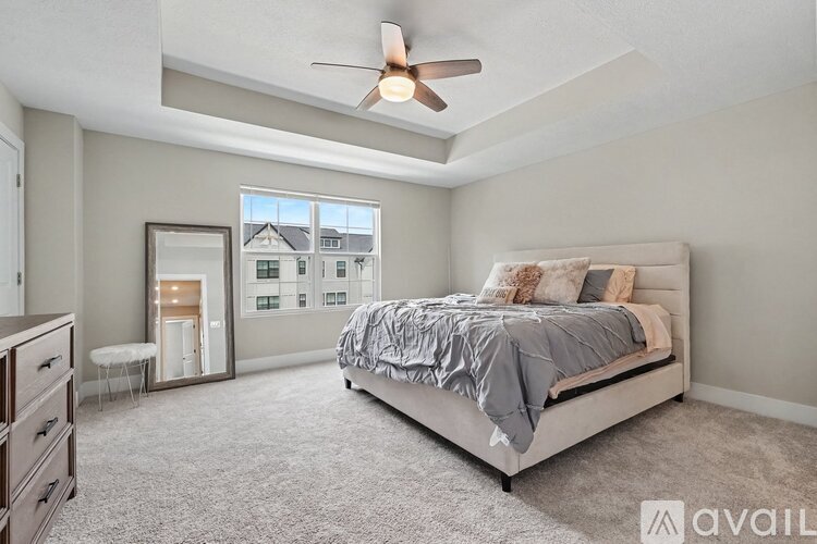 A bedroom with a large bed, a dresser, and a window overlooking a cityscape.