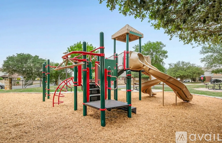 A playground with a red and green structure and a yellow slide.