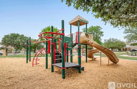 A playground with a red and green structure and a yellow slide.