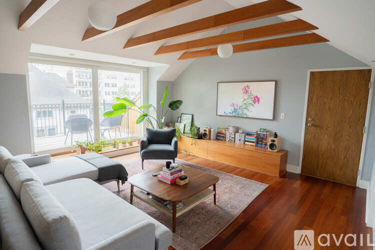 A living room with a grey couch, a wooden coffee table, a black chair, and a painting on the wall.