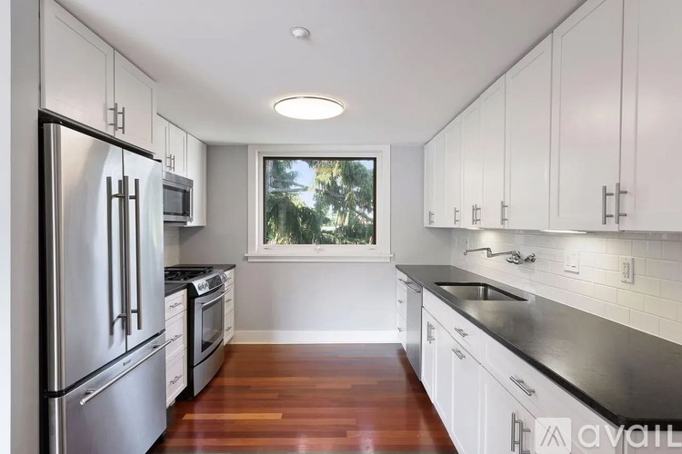 A kitchen with white cabinets and a window.