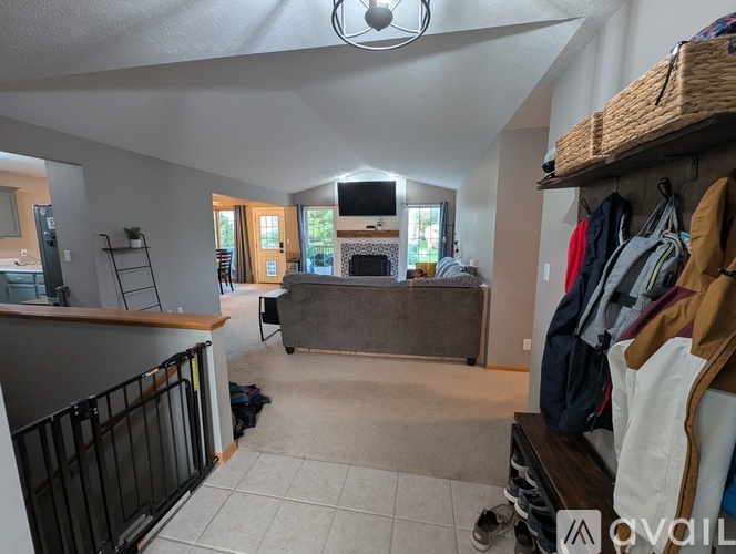 A room with a television, a couch, and a clothing rack.