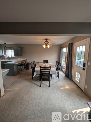 A dining room with a table set for four and a kitchen area in the background.