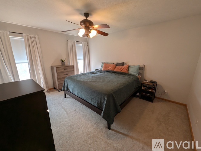 A bedroom with a bed, nightstand, and a ceiling fan.