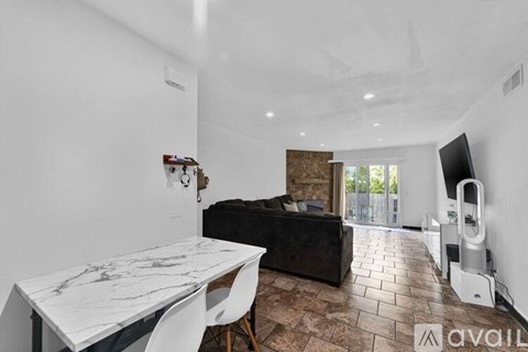 A living room with a black couch and a white marble table.