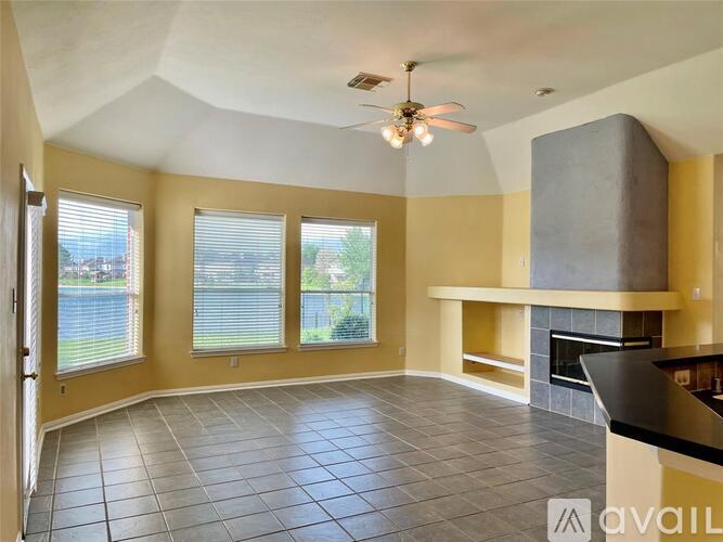 A spacious living room with a fireplace and a ceiling fan.