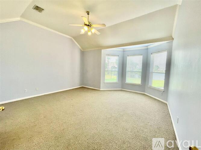A spacious room with a ceiling fan and carpeted floor.
