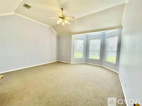 A spacious room with a ceiling fan and carpeted floor.