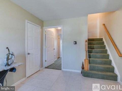 A hallway with a staircase and a door.