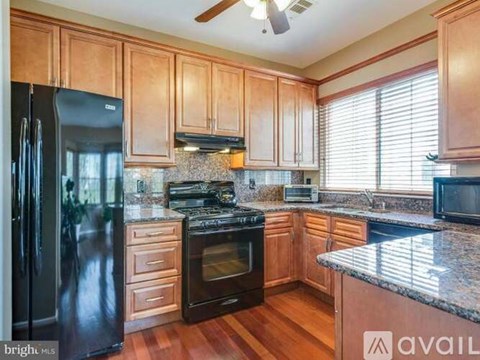 A kitchen with wooden cabinets and a black refrigerator.