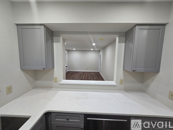 A kitchen with white countertops and cabinets with a logo on the bottom right.