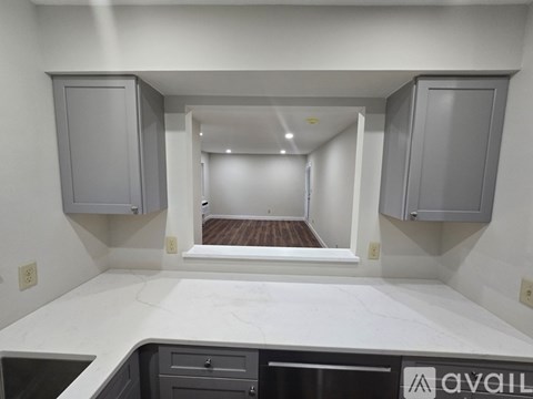 A kitchen with white countertops and cabinets with a logo on the bottom right.