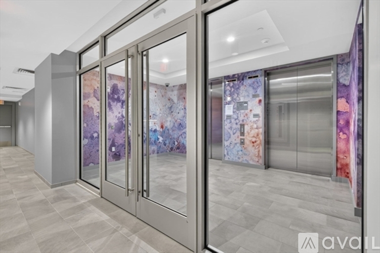 A hallway with a glass door and a purple wallpaper.