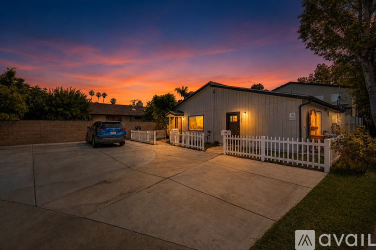 A house with a white picket fence and a car parked in the driveway.