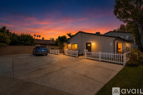 A house with a white picket fence and a car parked in the driveway.