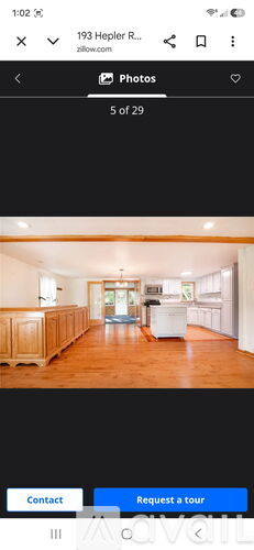 A room with wooden floors and a white refrigerator in the middle.