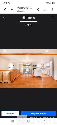 A room with wooden floors and a white refrigerator in the middle.