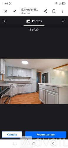 A kitchen with white cabinets and a wooden floor.