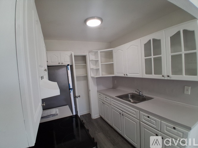A kitchen with white cabinets and a black floor.