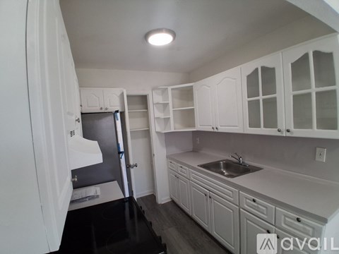 A kitchen with white cabinets and a black floor.
