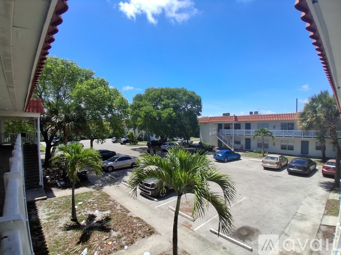 A sunny day in a parking lot with cars and palm trees.