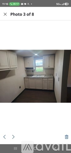 A photo of a kitchen with white cabinets and a window.