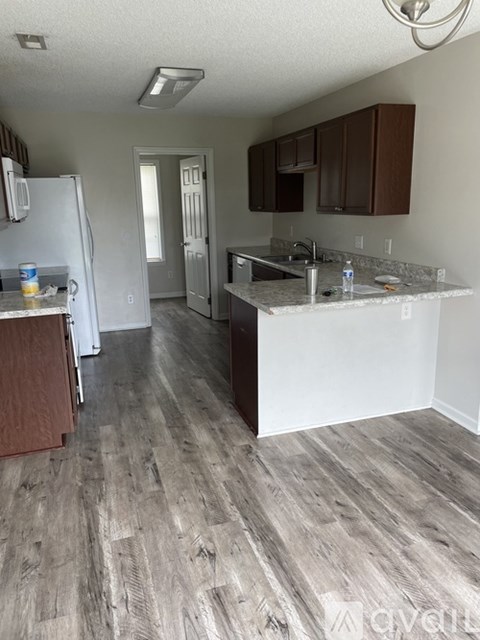 A kitchen with a white counter top and wooden floors.