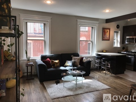 A living room with a black couch and a glass table.