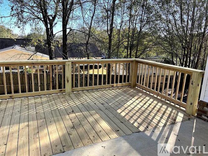 A wooden deck with a railing and trees in the background.