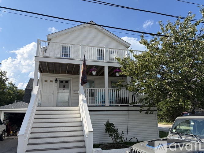 A two-story house with a white exterior and a balcony on the second floor.