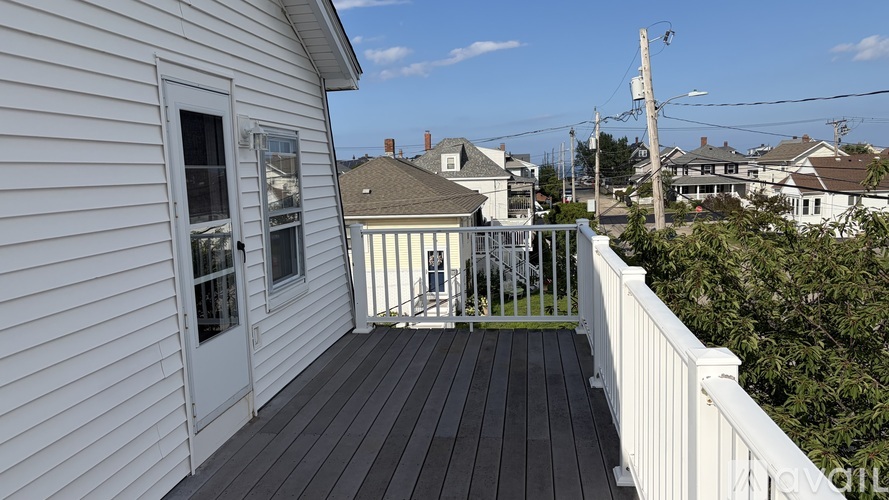 A white house with a deck and a view of the neighborhood.