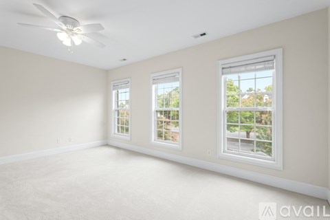 A room with a ceiling fan and three windows.