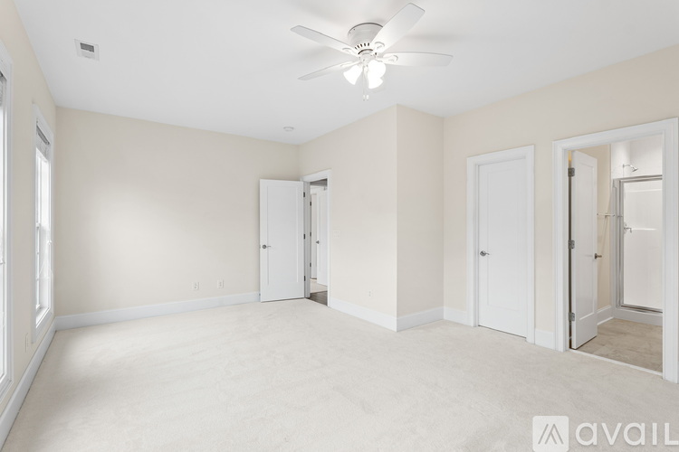 A spacious room with a ceiling fan and three doors.