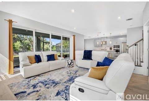 A living room with white furniture and a large window.