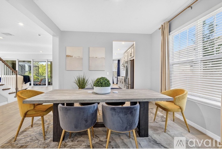 A dining room with a table surrounded by chairs.