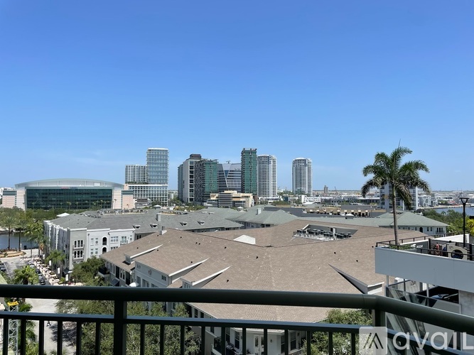A cityscape with buildings and palm trees under a clear sky.
