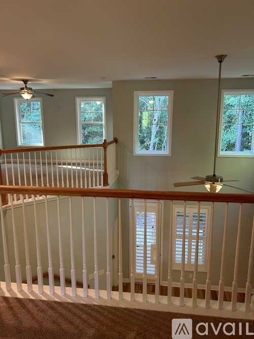 A room with a white railing and a ceiling fan.