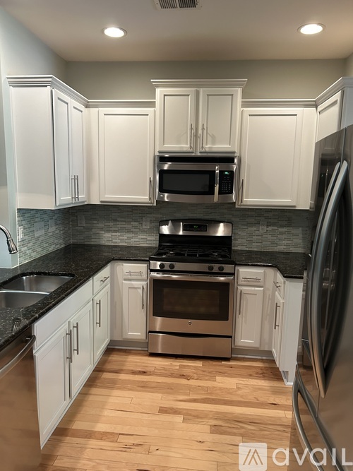 A kitchen with white cabinets and a black countertop.