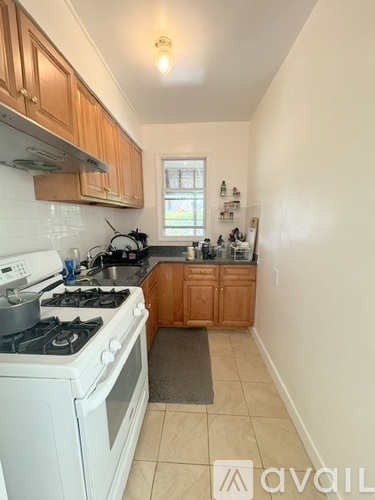 A kitchen with a white stove top oven and wooden cabinets.